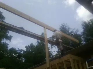 Carpenter setting a ridge beam over a new addition frame — Ice Dam Removal by Roofing Brothers in Stanardsville