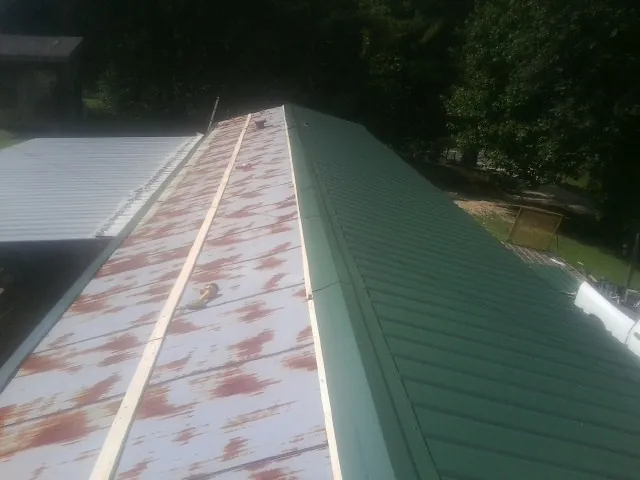 Old rusted panels beside newly installed green metal roofing — Wind Damage Roof Repair by Roofing Brothers in Stanardsville