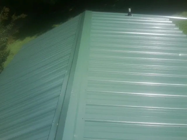 New green metal panels meeting at the ridge of a roof — Flat Roof Repair work by our crew in Stanardsville