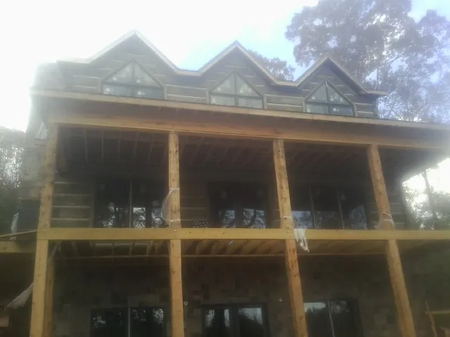 Dormers and porch framing on a large log home under construction — Roof Coating work by our crew in Stanardsville