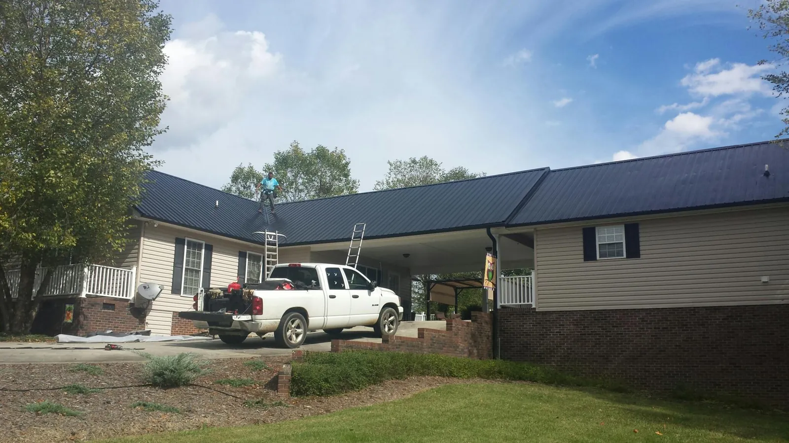 Black metal roof over a home and attached breezeway with ladders set in Stanardsville