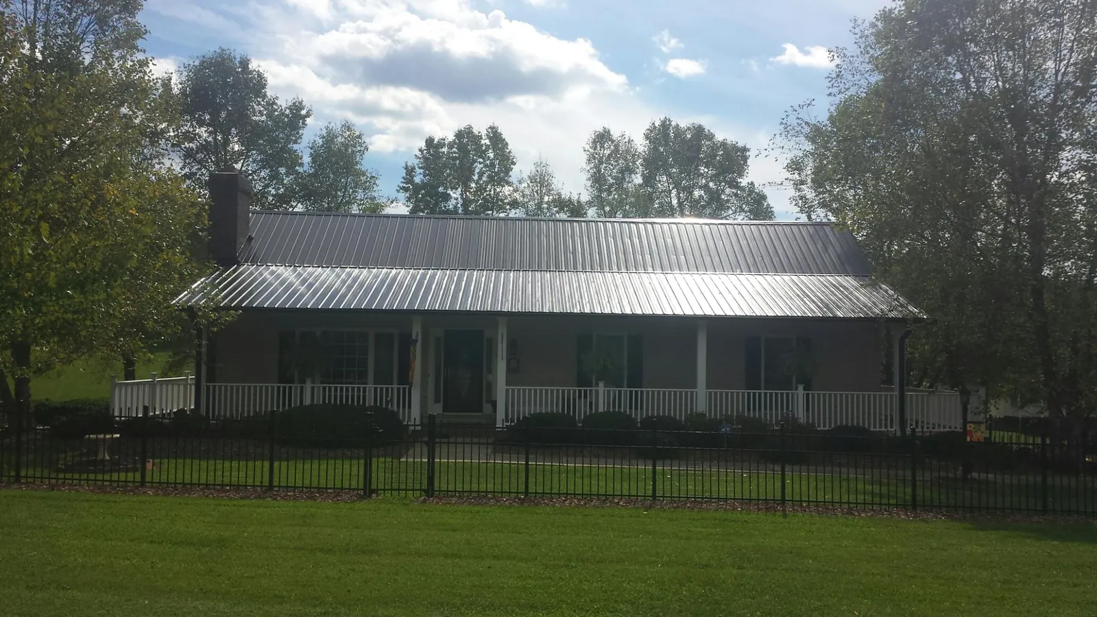 Gray metal roof on a brick ranch with a full width front porch — Gutter Guard Installation work by our crew in Stanardsville