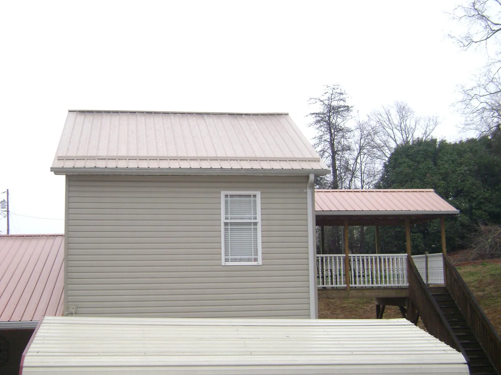 Tan metal roofs on a two story addition and attached porch, from a Roof Replacement job in Stanardsville