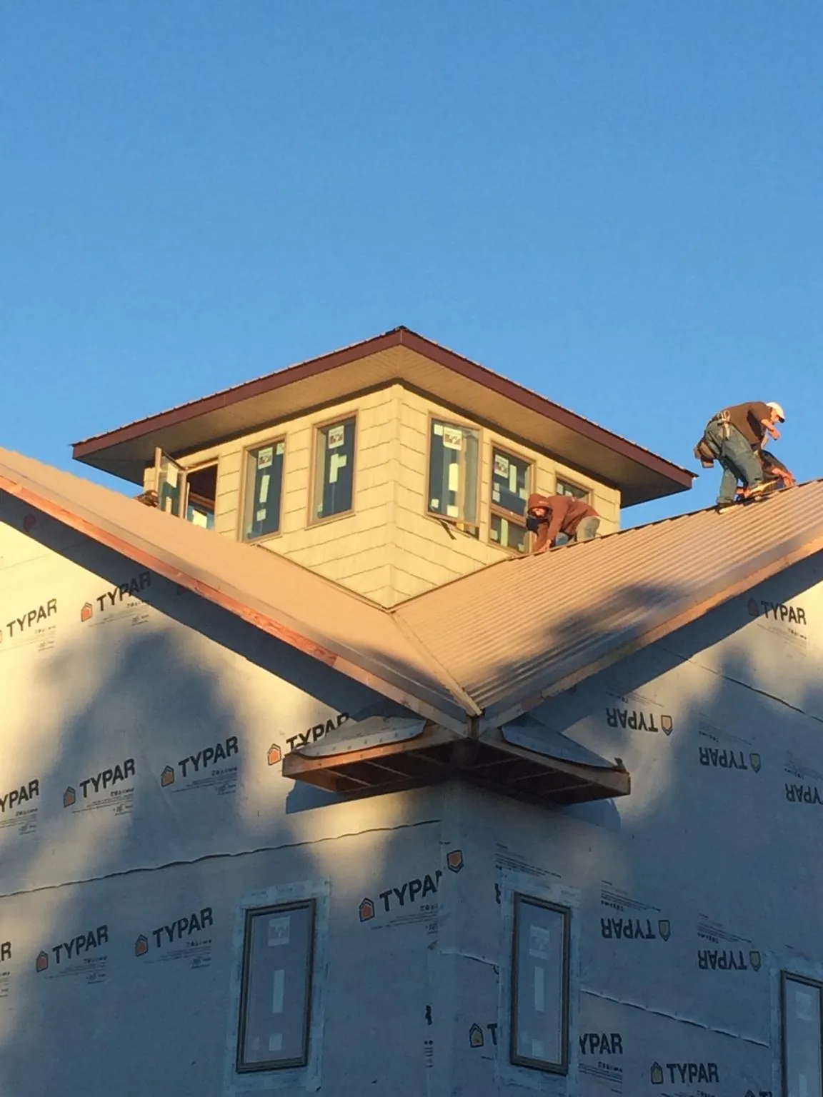 Roofers working around a rooftop cupola on a new metal roof at sunset — Roof Waterproofing in Stanardsville by Roofing Brothers